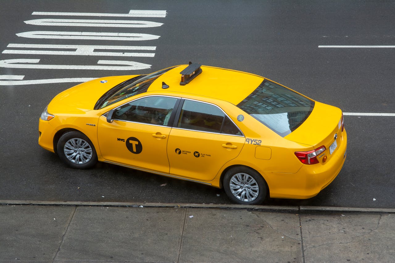 High angle view of a yellow NYC taxi on an asphalt road, a symbol of transportation in New York City.