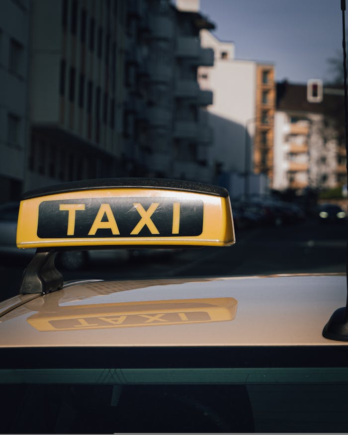Close-up of a taxi sign on a car roof with an urban city background.